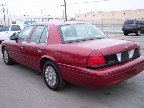 1999 Ford Crown Victoria - A red sedan is parked on a street with other vehicles visible in the background.
