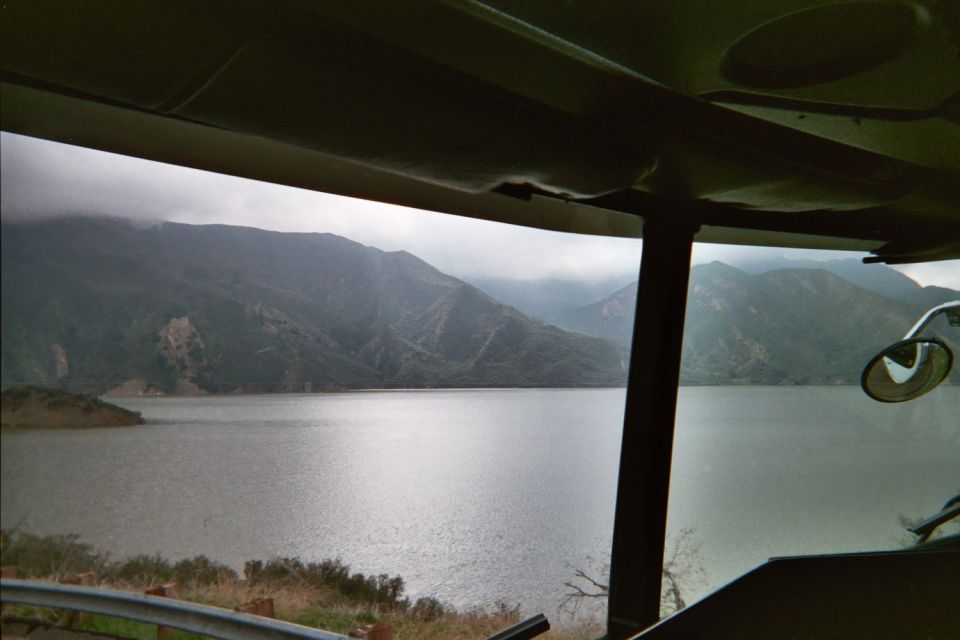 View of a misty mountain reservoir framed by a vehicle window