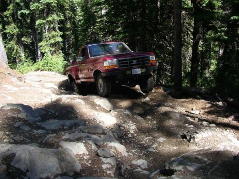 1992 Ford F-150 - Red 1992 Ford F-150 tackling a challenging rocky path in the woods.