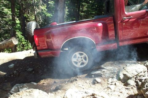1992 Ford F-150 - This red 1992 Ford F-150 is navigating a rocky trail, with smoke billowing from its rear tire.