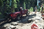 1992 Ford F-150 - A red 1992 Ford F-150 navigates a challenging, rocky path through a dense forest.