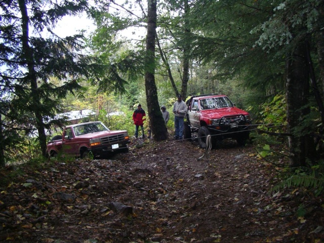 Red 1992 Ford F-150 pickup truck on a dirt path, front grille visible