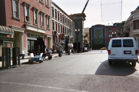 1990 Ford Bronco - Lighting equipment, carts and a white van sit on a studio-backlot street lined with brick building facades.