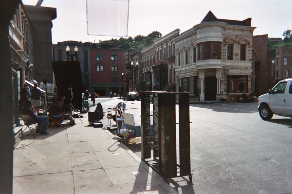 Crew with film lighting gear on a backlot street corner with a white van