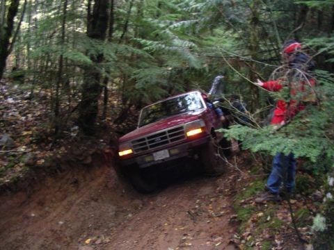1992 Ford F-150 - A 1992 Ford F-150 navigates a challenging, wooded trail with a person visible in the driver's seat.