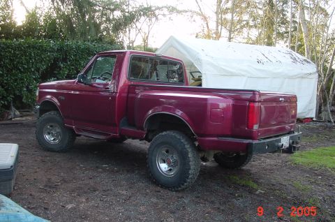 1992 Ford F-150 - This pickup truck is parked outdoors on a dirt lot, with a white tent and trees visible behind it.
