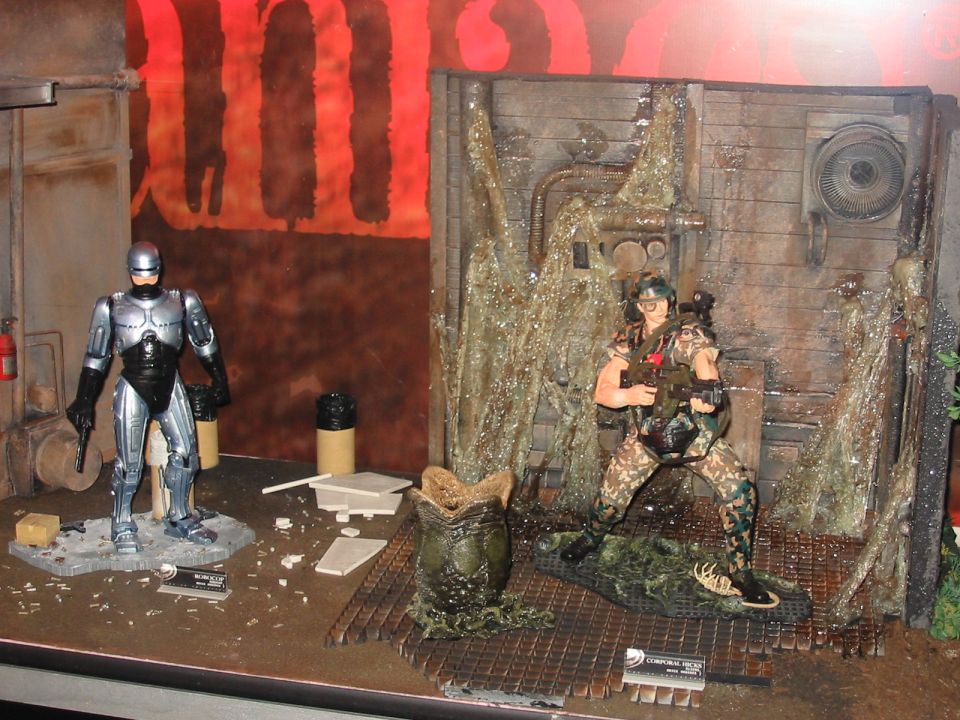 RoboCop and a soldier figure stand in a diorama with an alien egg