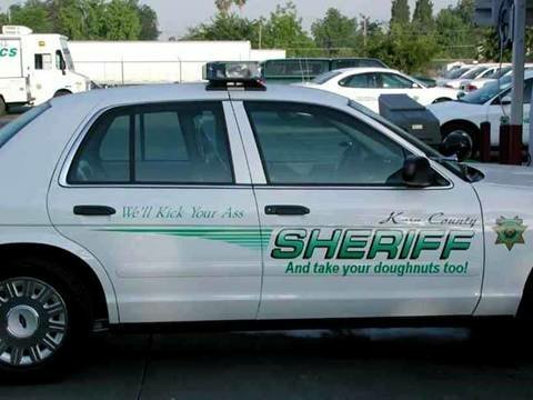 1990 Ford Bronco - A Sheriff's car is parked with other vehicles in the background.