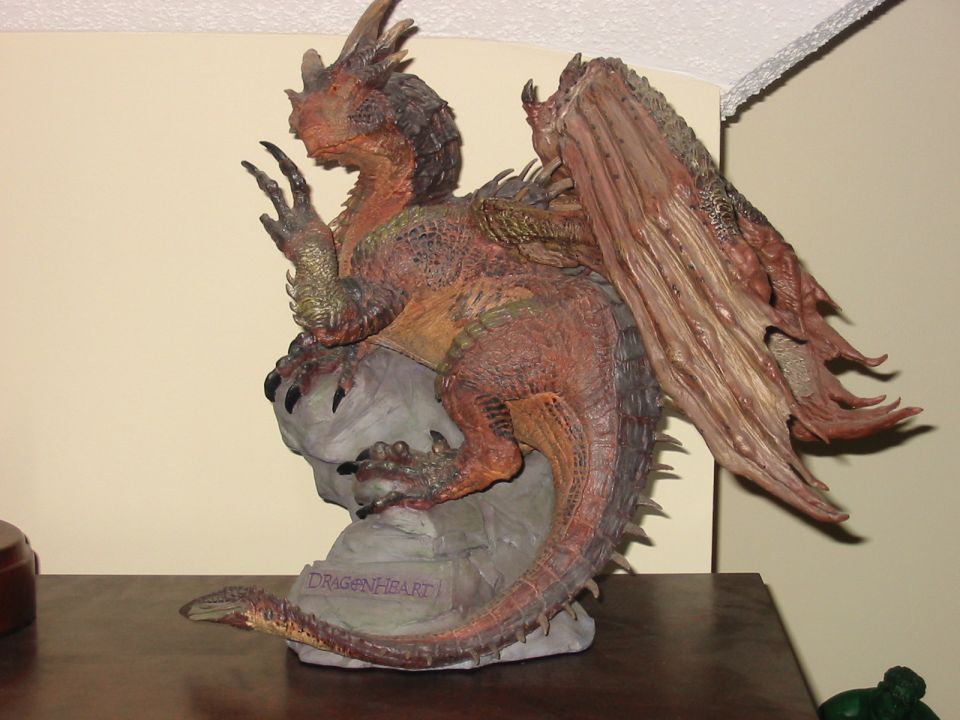 Dragon figurine on a rock base with 'DRAGONHEART' text, on a wooden surface