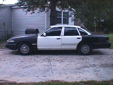 1994 Ford Crown Victoria - A two-tone black and white Ford Crown Victoria is parked on a concrete driveway.
