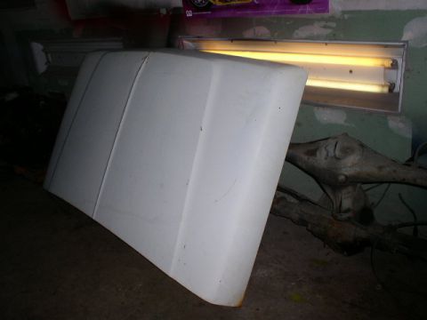 1979 Ford Bronco - A white vehicle hood is shown indoors, with a fluorescent light fixture in the background.