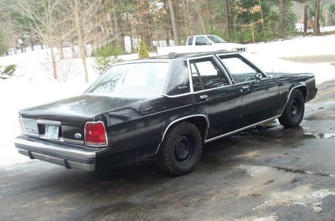 1991 Ford Crown Victoria LTD - This black sedan has a boxy body style typical of cars from the early 1980s, not 1991.