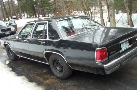 1991 Ford Crown Victoria LTD - A black 1991 Ford Crown Victoria LTD sedan is parked outdoors with another vehicle visible in the background.
