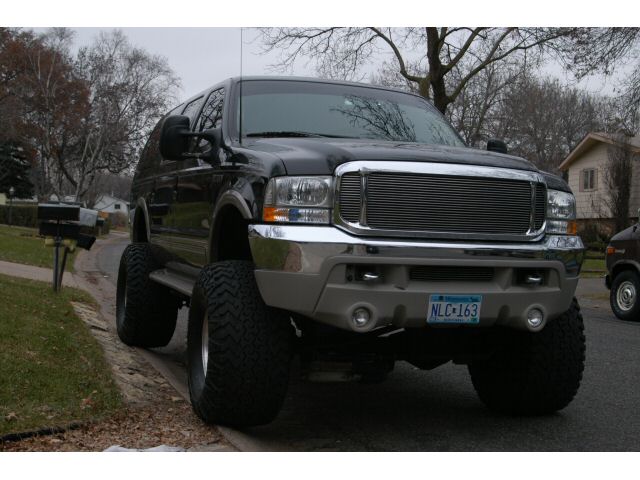 Front view of a lifted black Ford Excursion with chrome grille and bumper