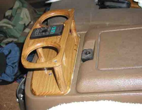 1988 Ford Bronco - Interior shot of a custom oak-finished wood console插 panel fitted alongside a tan dashboard, with two round cutouts for gauges or cup holde…