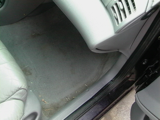 Interior view of a car's passenger side floor and lower dashboard with a vent