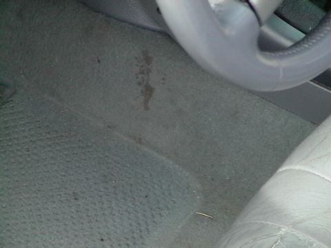 1995 Ford Contour - The interior floor mat shows a stain and a portion of the steering wheel is visible.