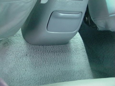 1995 Ford Contour - This image shows the interior console and carpet of a vehicle, with a small storage compartment visible.