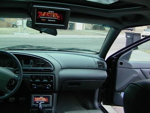 1995 Ford Contour - The interior of a car features two screens, one mounted overhead and another in the dash, displaying media content.