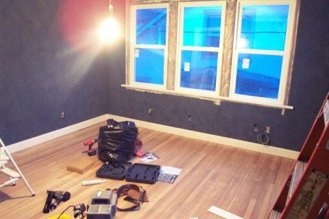 1985 Ford LTD Crown Victoria - Construction materials and tools are scattered on the floor of a room with blue-covered windows.