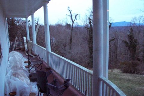 1985 Ford LTD Crown Victoria - A porch overlooks a wooded landscape with distant hills under an overcast sky.