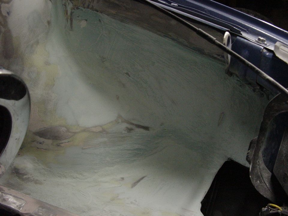 Close-up of a car's engine bay with some repair material applied
