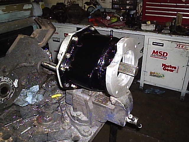 Differential and large brake assembly mounted on a stand in a cluttered shop