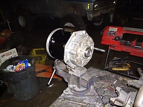 1984 Ford Bronco II - A vehicle transmission component is secured in a vise, with a truck and workshop equipment visible in the background.
