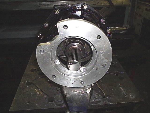 Close-up of a splined shaft inside a black housing with a silver flange, held in a vise