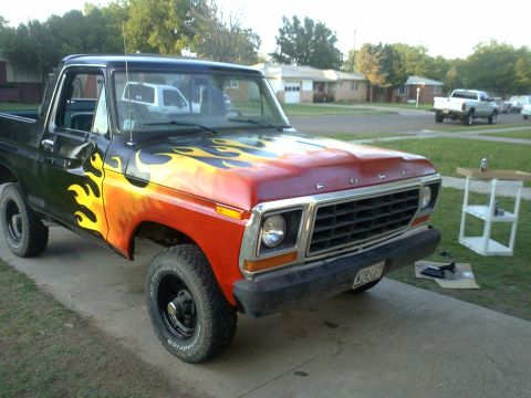 1978 Ford Bronco - A 1978 Ford Bronco with custom flame paint is parked outside a suburban home.