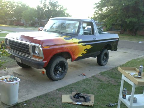 1978 Ford Bronco - This truck features a striking flame graphic design on its side, with a red front fading into a black rear.