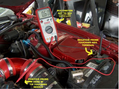 1996 Ford Probe - A multimeter is used to measure voltage in a car's engine bay, with probes connected to the battery and a sensor.