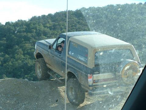 1991 Ford Bronco - A Ford Bronco navigates a steep, dusty incline on a sunny day.
