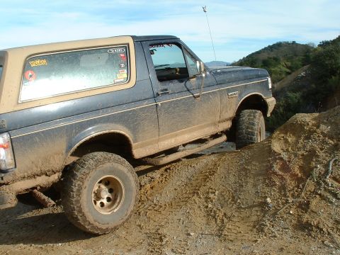 1991 Ford Bronco - This 1991 Ford Bronco is navigating a muddy off-road trail under a clear sky.