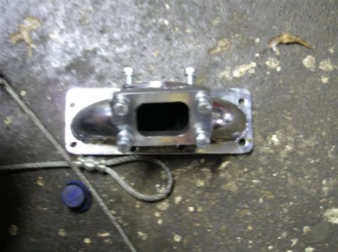 1994 Ford Probe - A metal exhaust manifold part is shown on a concrete floor, with a cable and blue cap nearby.