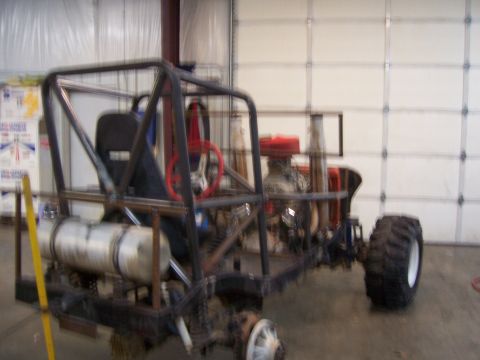 1999 Jeep TJ - A custom-built buggy with a roll cage and exposed engine sits in a garage.