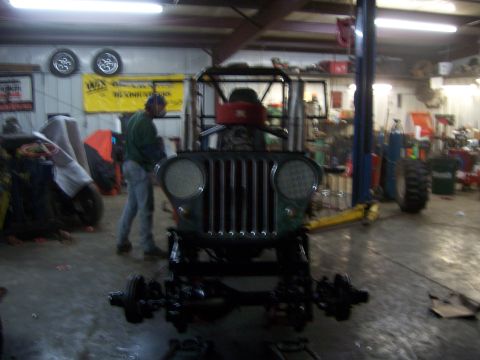1999 Jeep TJ - A vintage Jeep, likely from the 1940s, is in a workshop with its front axle removed.