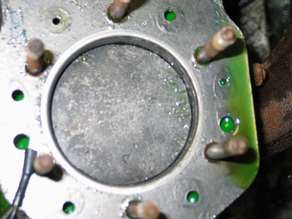 Close-up of an engine cylinder with green fluid pooled around the edges