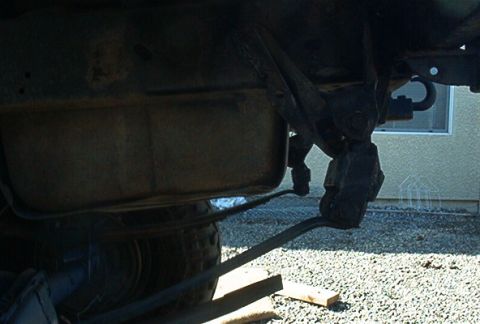 1986 Ford Bronco - A close-up view of the underside of a vehicle, revealing its fuel tank and suspension system.