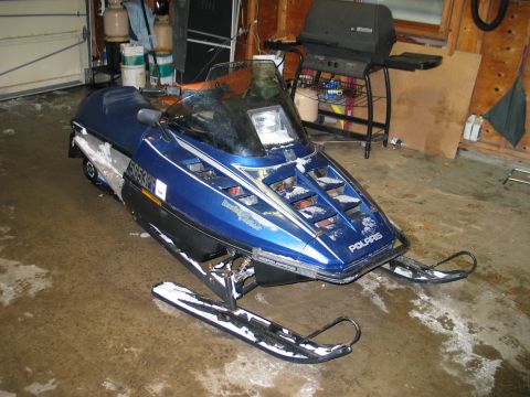 1990 Ford Mustang - Blue Polaris snowmobile with visible model name and registration number in a garage.