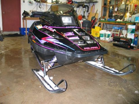 1990 Ford Mustang - A black Polaris snowmobile with colorful decals sits in a cluttered garage.