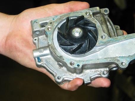 1990 Ford Mustang - A hand holds a car water pump, showing the internal impeller and metal casing.