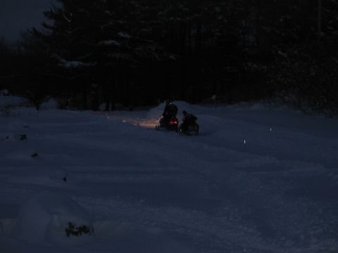1990 Ford Mustang - Two snowmobiles are seen riding through a snowy landscape at night.