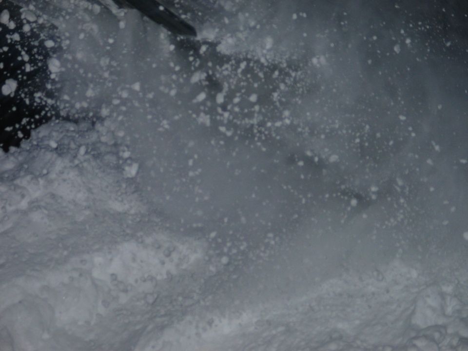 Snow spraying up from a snowboarder carving down a slope