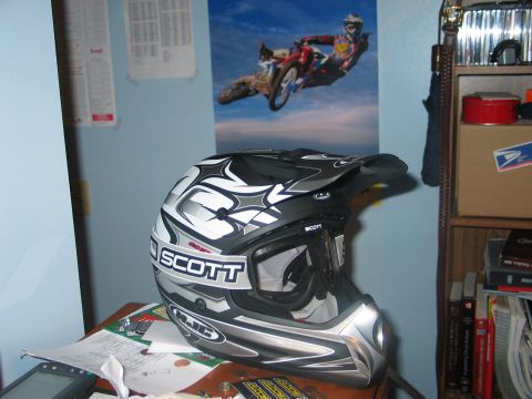 1990 Ford Mustang - A Scott motocross helmet sits on a desk, with a poster of a motocross rider in mid-air on the wall behind it.