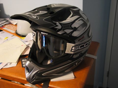 1990 Ford Mustang - A black dirt bike helmet with Scott goggles is displayed on a wooden surface next to papers.