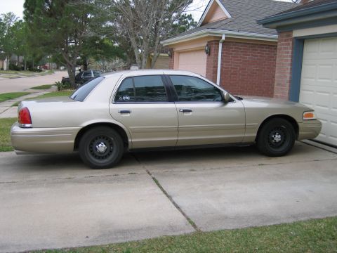 2000 Ford Crown Victoria - Side view of a gold 2000 Ford Crown Victoria parked in front of a garage.