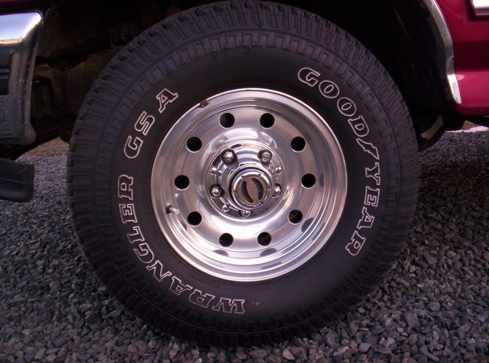 Red vehicle's front wheel with Goodyear Wrangler GSA tire and chrome rim