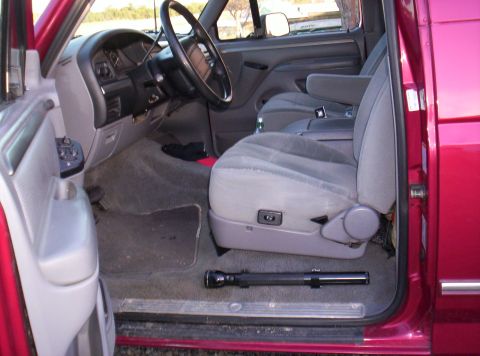 1995 Ford Bronco - The interior of a red 1995 Ford Bronco is visible, the driver's seat, dashboard, and door panel.