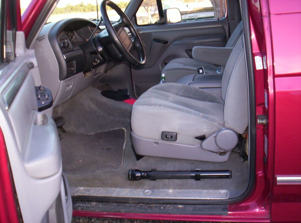 Interior of a red 1995 Ford Bronco showing the driver's seat and dashboard